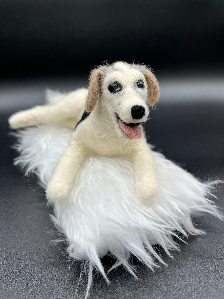  A needle felted pet portrait of a white dog on a white fluffy pillow.